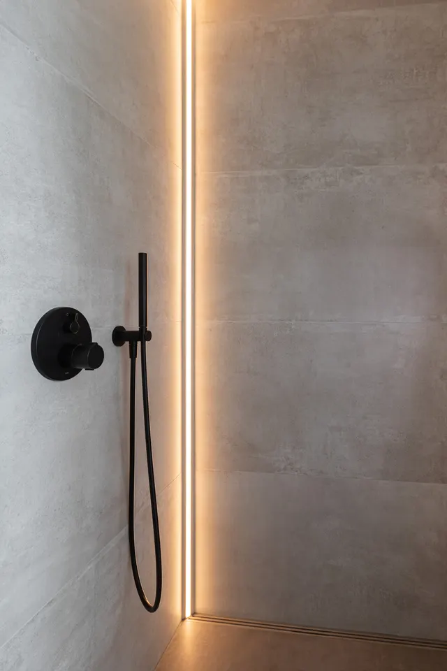 Dusche mit Lichtleiste und schwarzer Armatur